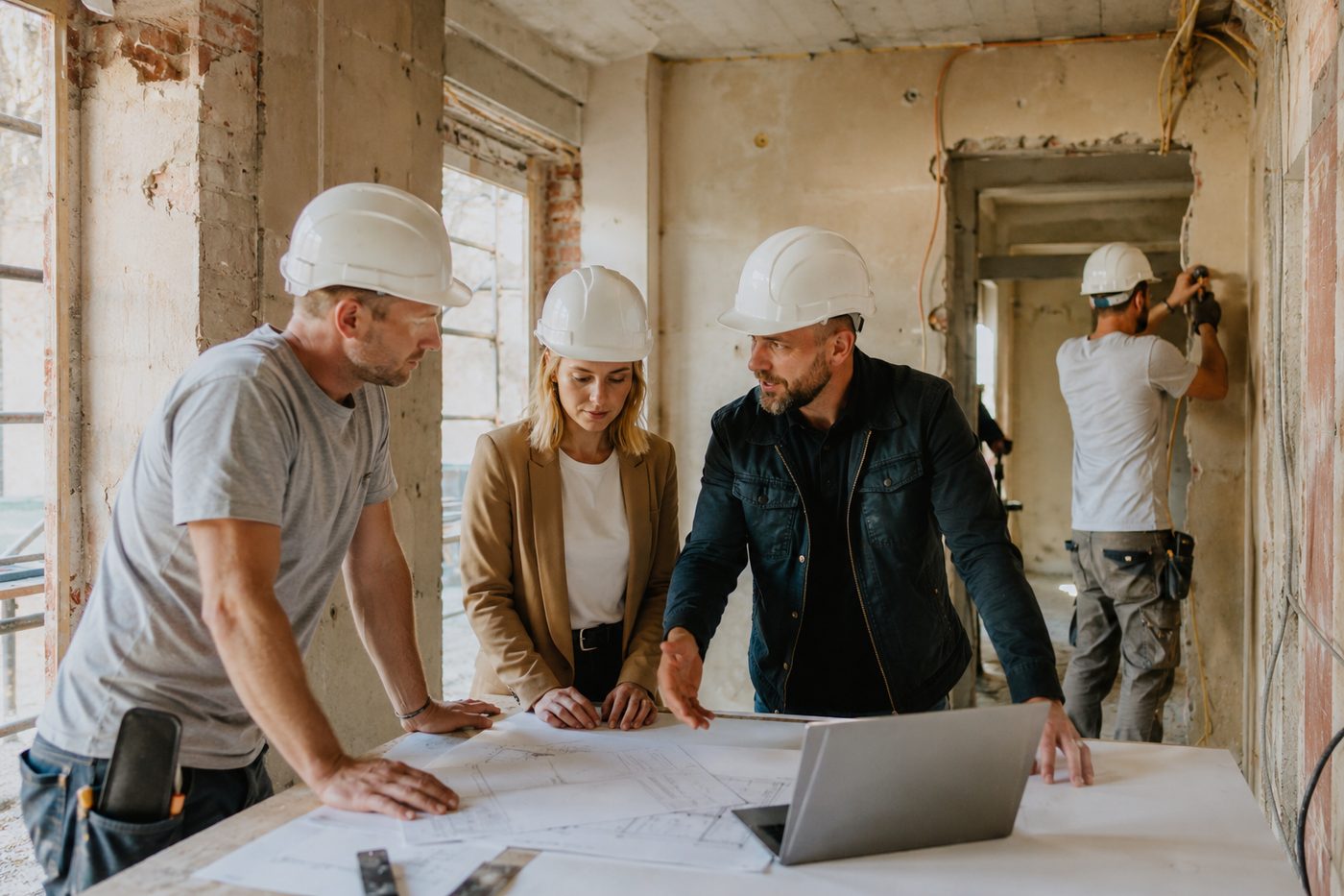 Beratungsgespräch mit Bauplan auf der Baustelle